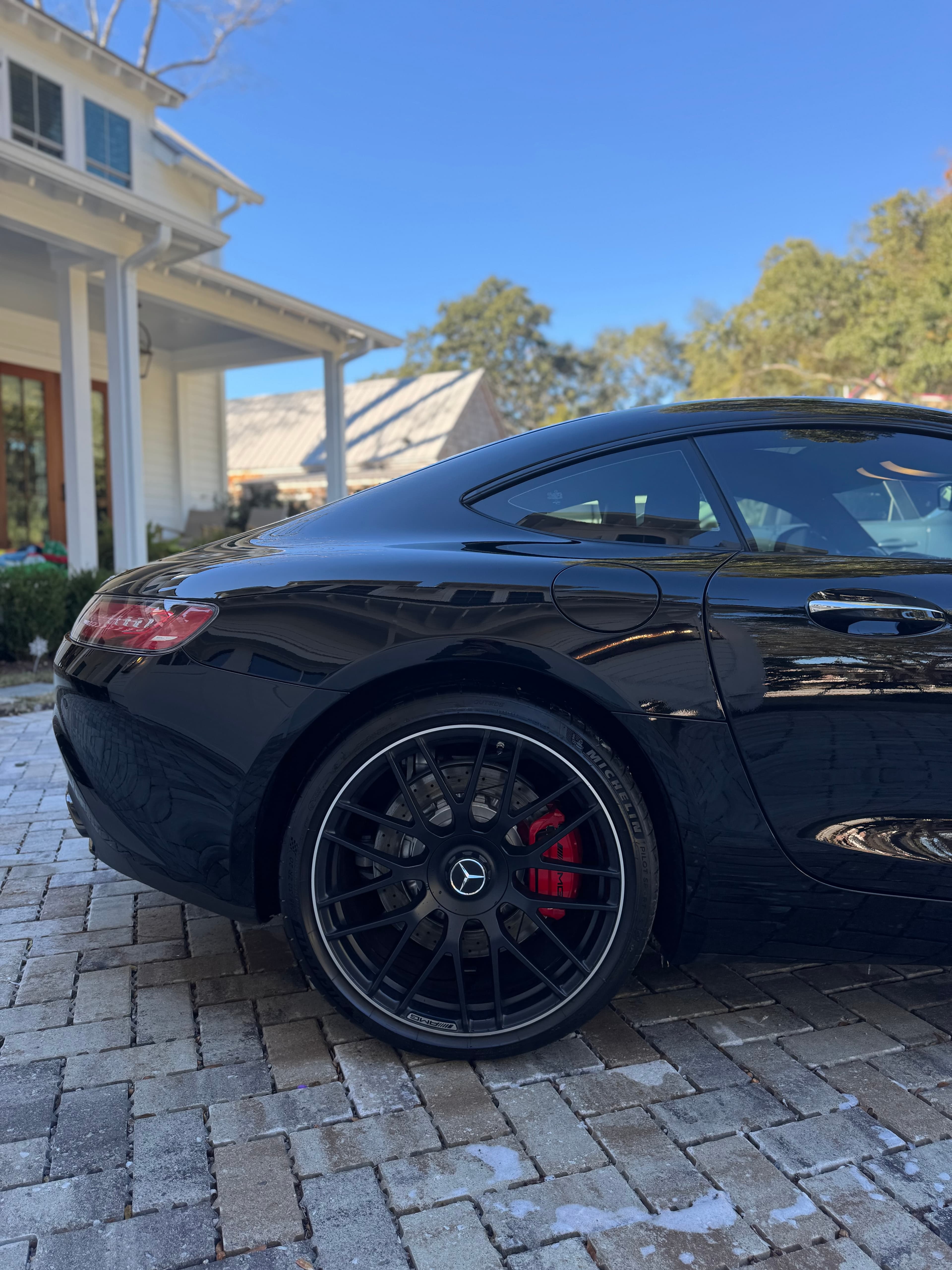 Rear quarter of a black Mercedes-AMG GT showing gloss black wheel and red brake caliper