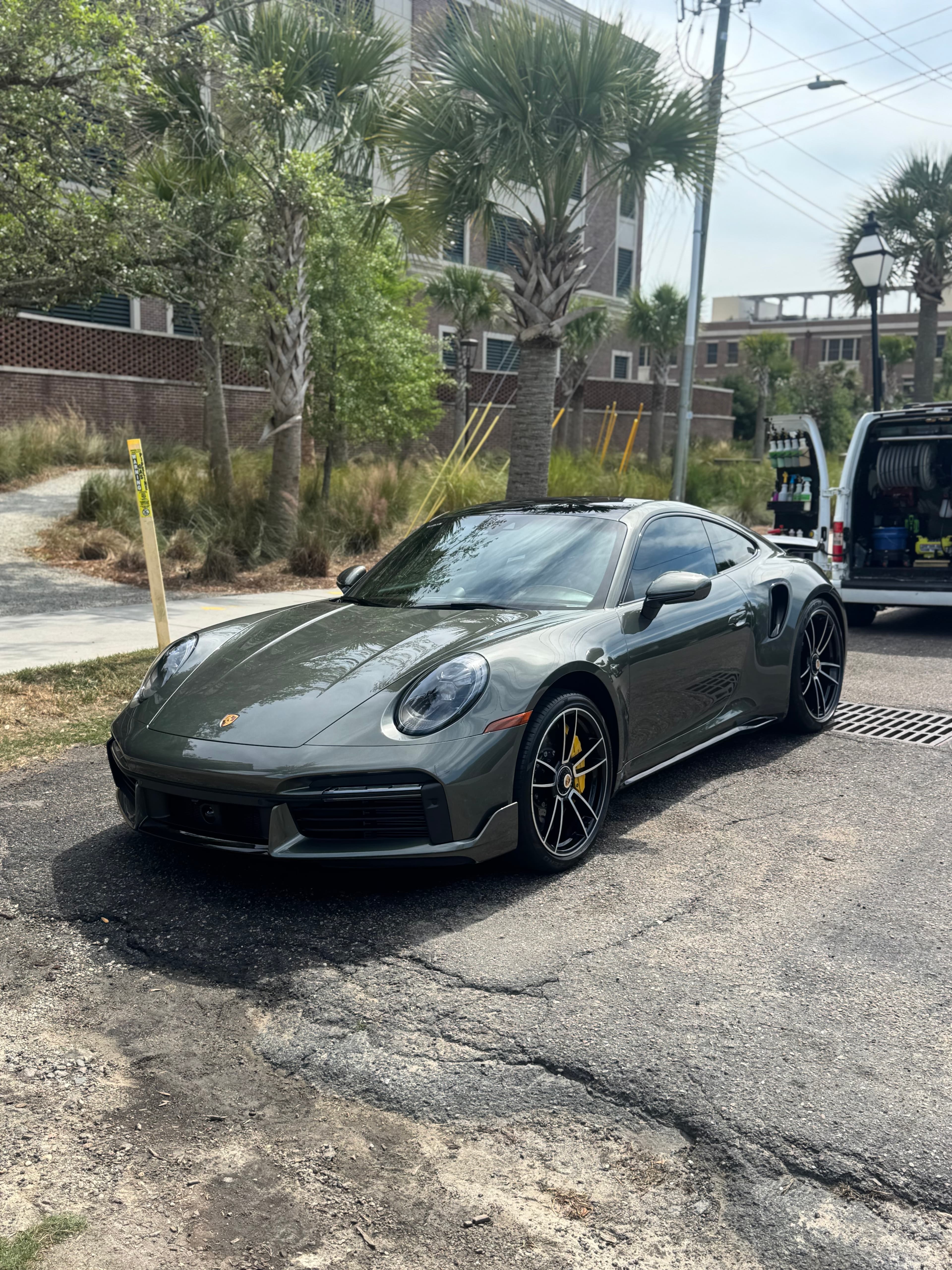 Glossy green Porsche 911 Turbo S coupe detailed and parked beside the mobile detailing van