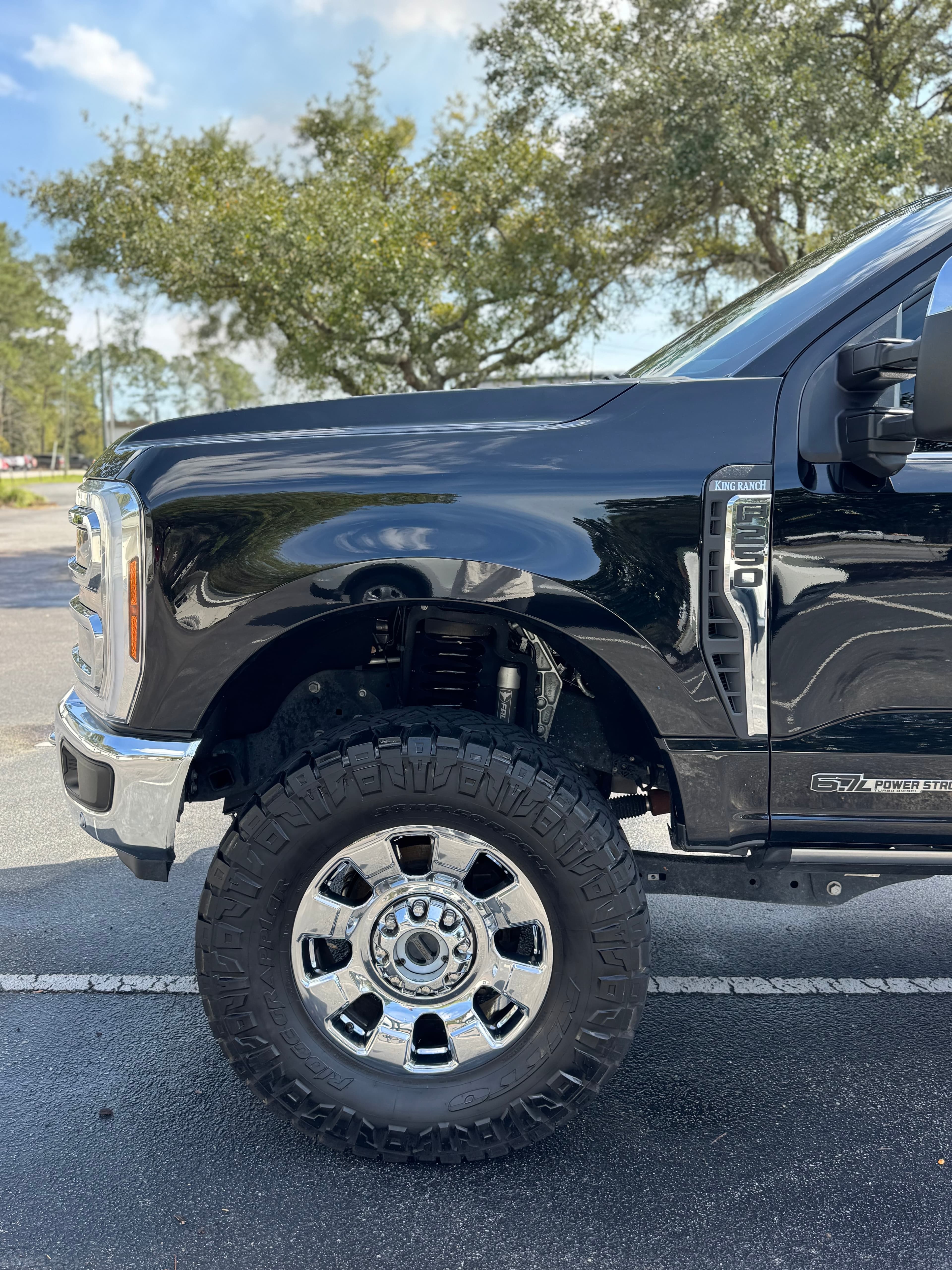 Glossy black truck fender and chrome wheel detail after wash and wax