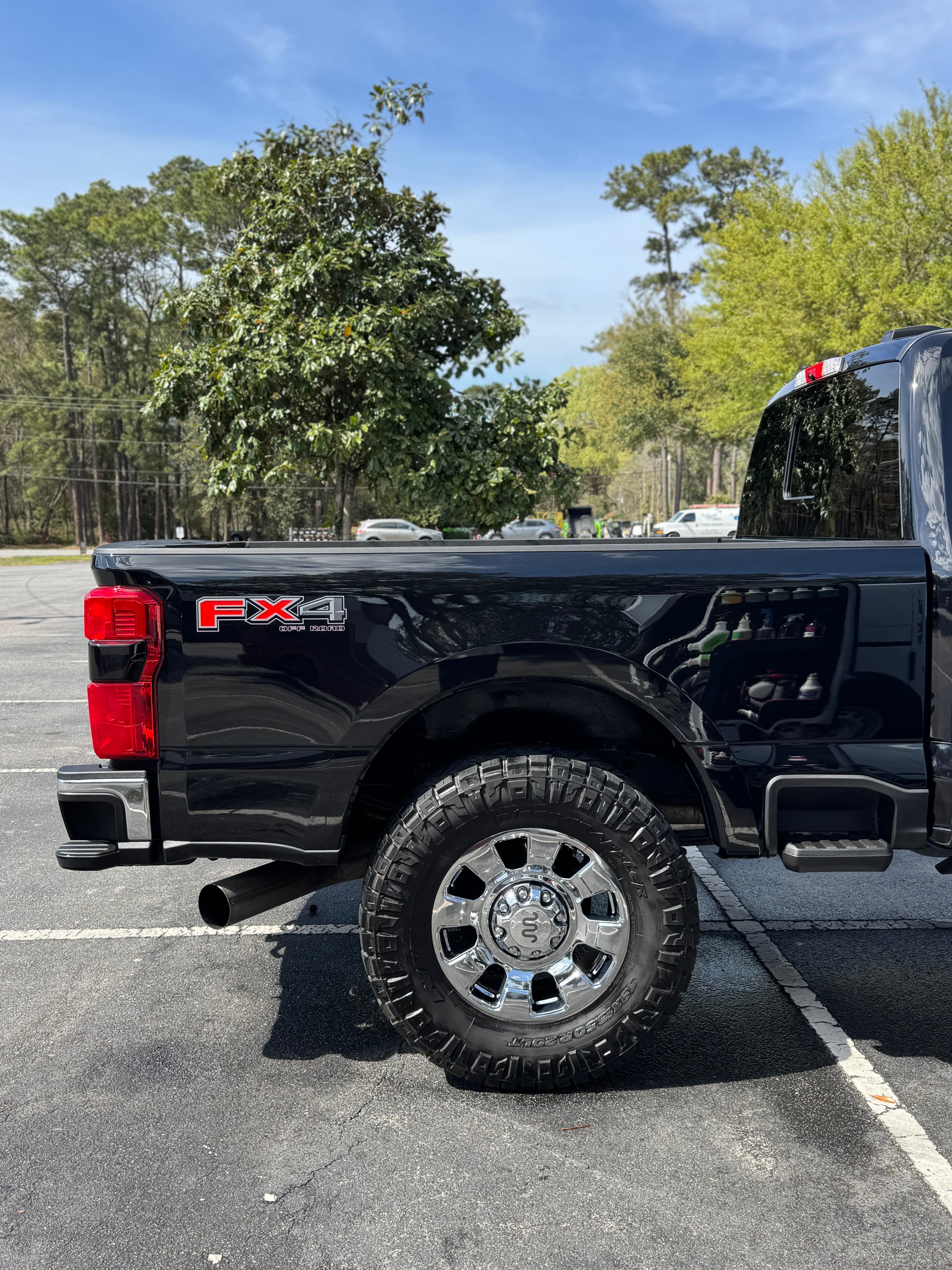 Glossy black Ford Super Duty truck bed and chrome wheel after detailing