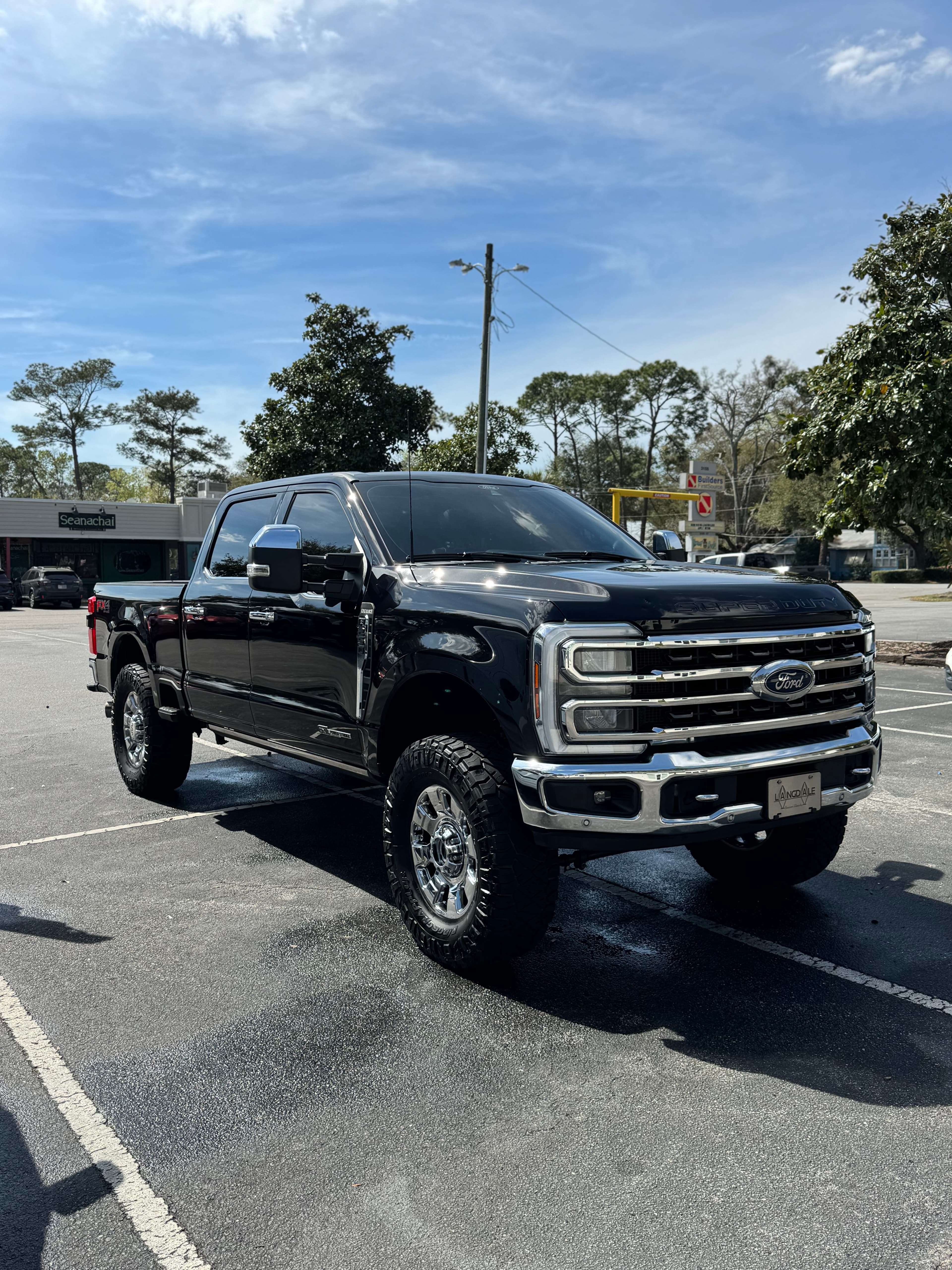 Clean lifted black Ford Super Duty truck shining in a parking lot after detail